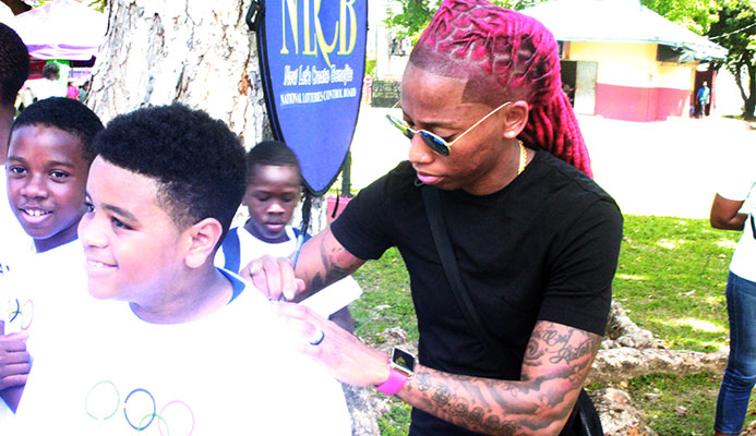 Commonwealth gold medallist and Olympic finalist Michelle Lee Ahye signs an autograph for a boy at Olympic Day, Woodford Square, Port of Spain yesterday. PHOTO BY ERIQUE ASSON