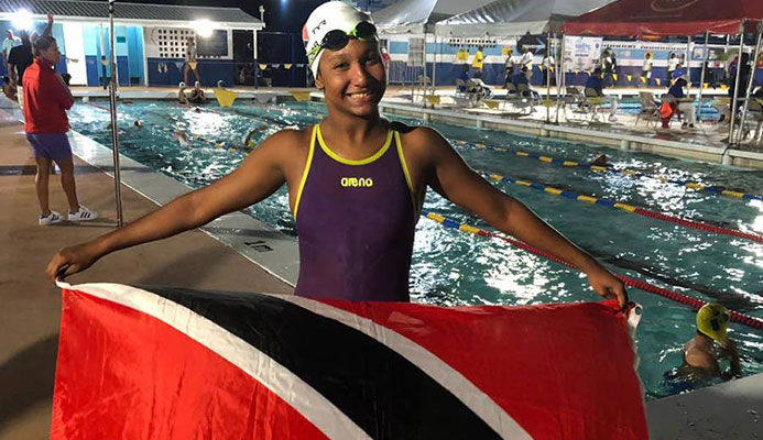 Jada Chatoor holding up the TT flag at the Carifta Championships in Barbados. PHOTO BY SHERDON PIERRE