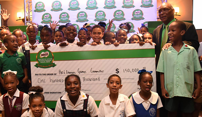 Primary school children display a cheque for $150,000 issued by title sponsor of the 32nd Kelvin Nancoo Games 2019. At right stands chair of the Milo West Games Kelvin Nancoo.