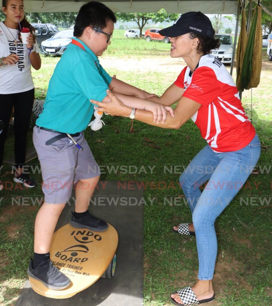 Belinda Bain-Hares of the Surfing Association of TT shows a St Patrick's Newtown Boys RC student how to balance on a surfboard, during the TT Olympic Committe Olympic Day celebrations, at the Queen's Park Savannah, Port of Spain on June 21. - Photo by Angelo Marcelle (Image obtained at newsday.co.tt)