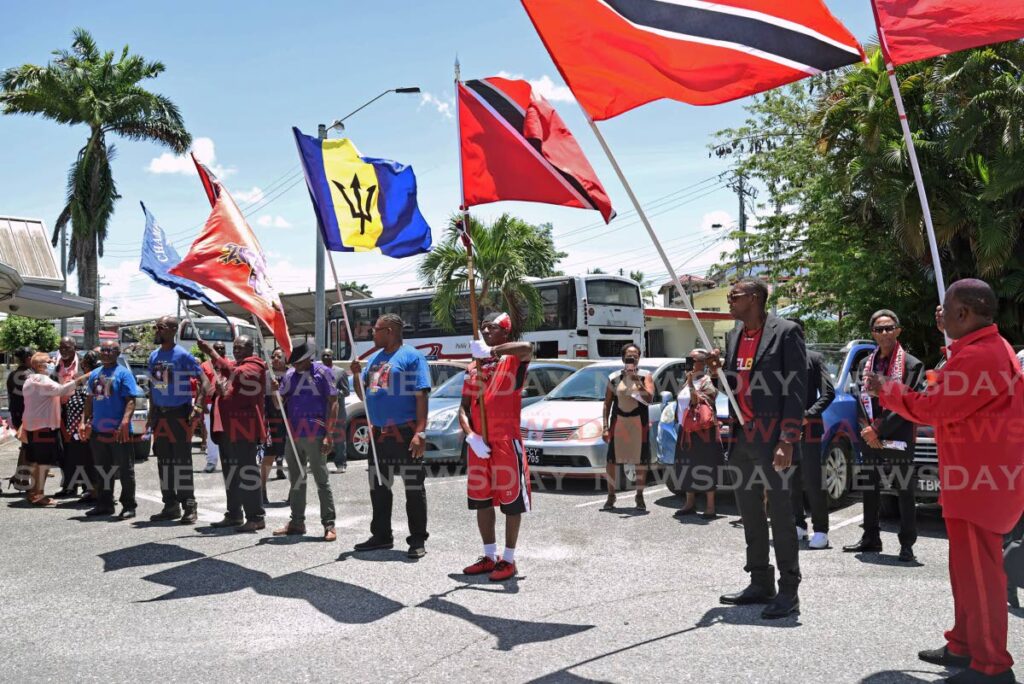 KEEPING THE FLAG FLYING: Grand send off for the late Joey Richardson, also known as the flagman, at his funeral at the St Phillip and St James RC Church in Chaguanas on September 4. Men raise their flags as the casket is carried out of the church. - Photo by Venessa Mohammed (Image obtained at newsday.co.tt)